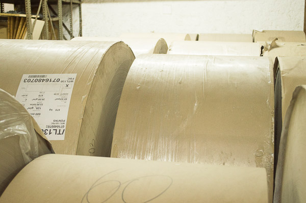 Fábrica: Bobinas de papel kraft em estoque para produção de caixas e sacolas.